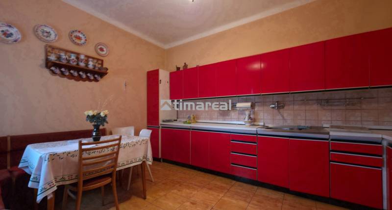 Eine Küche in einem Einfamilienhaus mit roter Küchenzeile und Esstisch, dekoriert mit Keramiktellern.