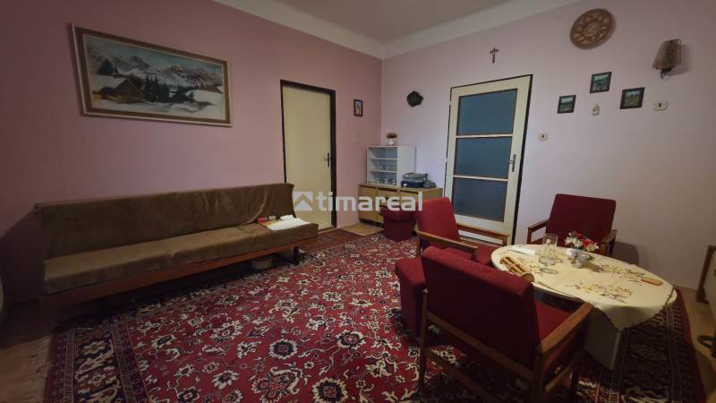 Wohnzimmer in einem Einfamilienhaus mit rotem Teppich und Holzmöbeln.