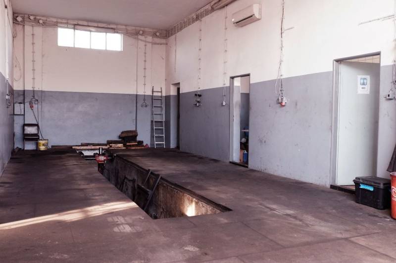 Reparatur von Autos in Produktionsräumen mit Holzbodenoptik und Wartungsgrube.