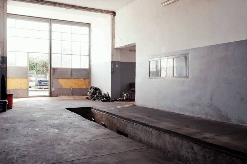 Produktionsräume mit großen Fenstern, einem Garagentor und einem Boden mit Holzdekor.