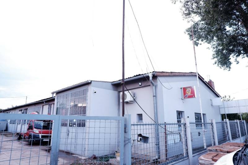 Produktionsräume in der Stadt Veľké Úľany mit grauer Fassade und einem roten Auto hinter dem Zaun.