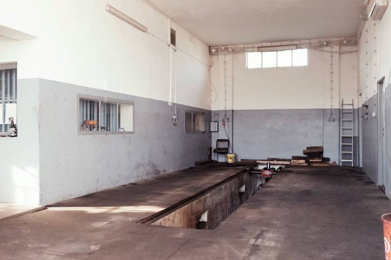 Produktionsräume mit Ausstattung, Betonboden, graue Wände, Wartungsbereich für Fahrzeuge.