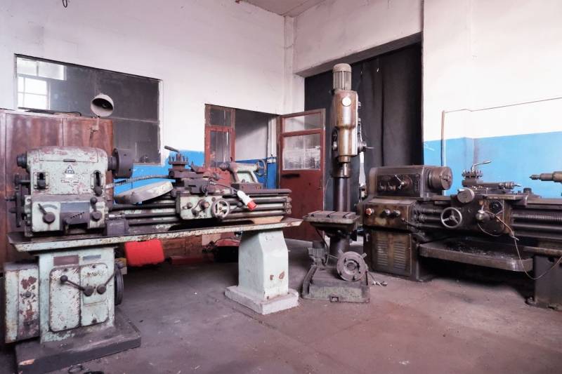 Produktionsräume mit alten Maschinen und unverputzten Wänden, Boden mit Holzdekor.