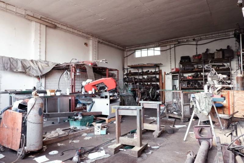 Pohľad do výrobných priestorov s dielenským zariadením, stoličkami a nástrojmi.