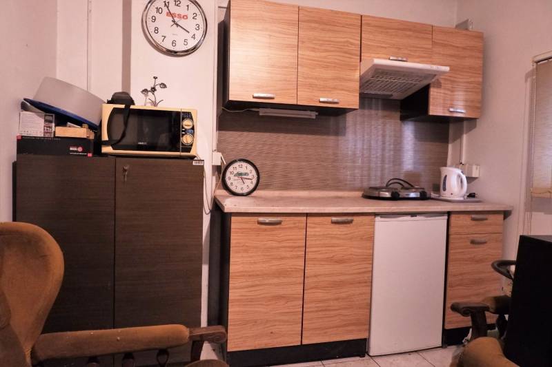 Küche mit Holzdekor, Mikrowelle, zwei Uhren und Geräten auf der Arbeitsplatte.