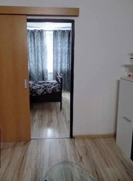 Innenraum mit Holzboden, Schiebetüren und schwarz-weißen Vorhängen in einer 3-Zimmer-Wohnung.