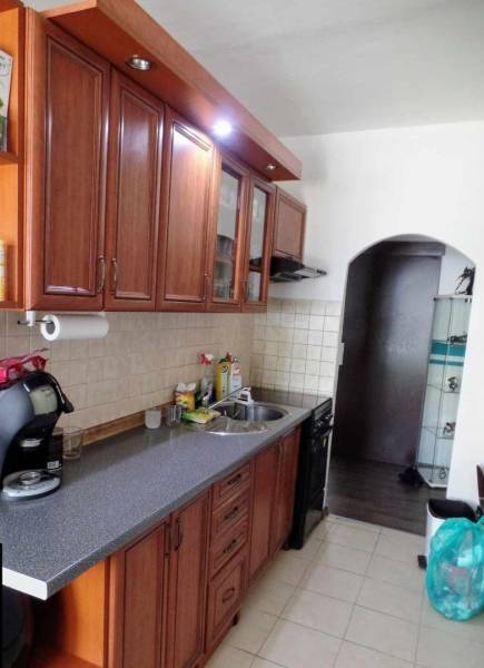 Küche in einer 3-Zimmer-Wohnung mit Holzschränken und einer gefliesten Wand über der Arbeitsplatte.