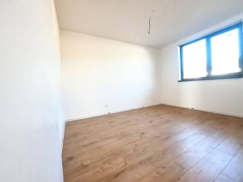 Ein leerer Raum mit Holzboden und einem großen Fenster in einem Einfamilienhaus.