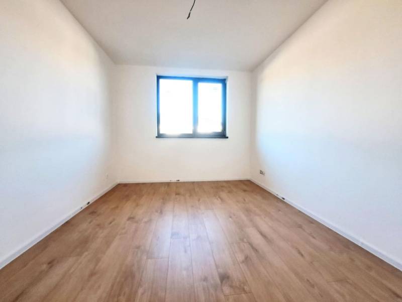 Blick in ein Zimmer mit weißen Wänden und einem Boden in Holzoptik in einem Einfamilienhaus.