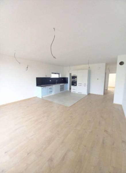 Küche mit weißen Schränken, dunkler Arbeitsplatte und Bodenbelag in Holzoptik.