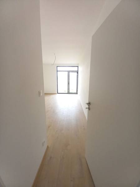 Innenraum eines Einfamilienhauses mit Holzdekorboden und großem Fenster.