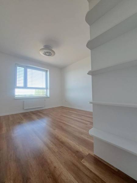 Ein Zimmer in einer 2-Zimmer-Wohnung mit einem Boden in Holzoptik, hellen Wänden und einem Fenster.