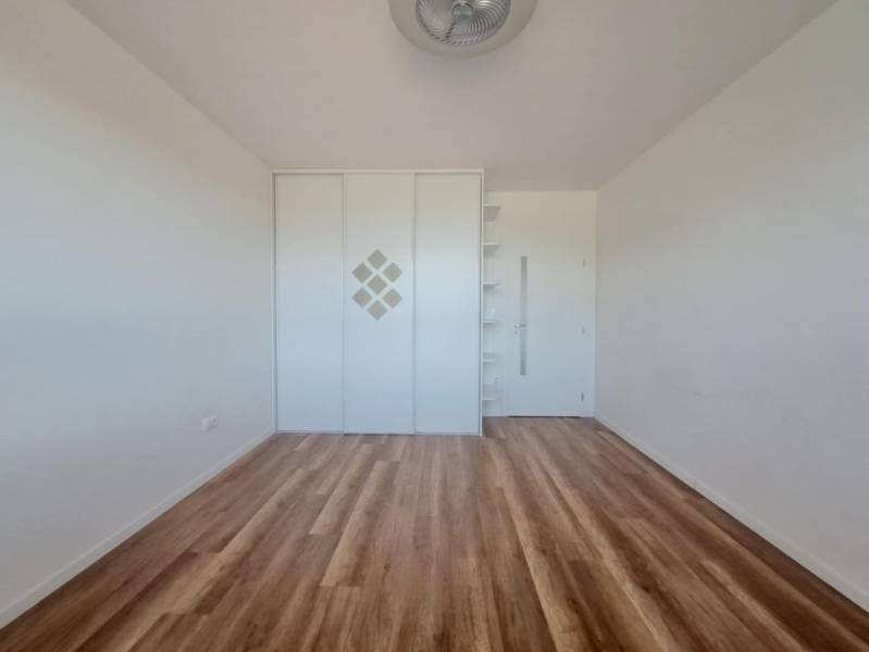 Ein Zimmer mit Holzboden, Einbauschrank und Regalen in einer Zweizimmerwohnung.