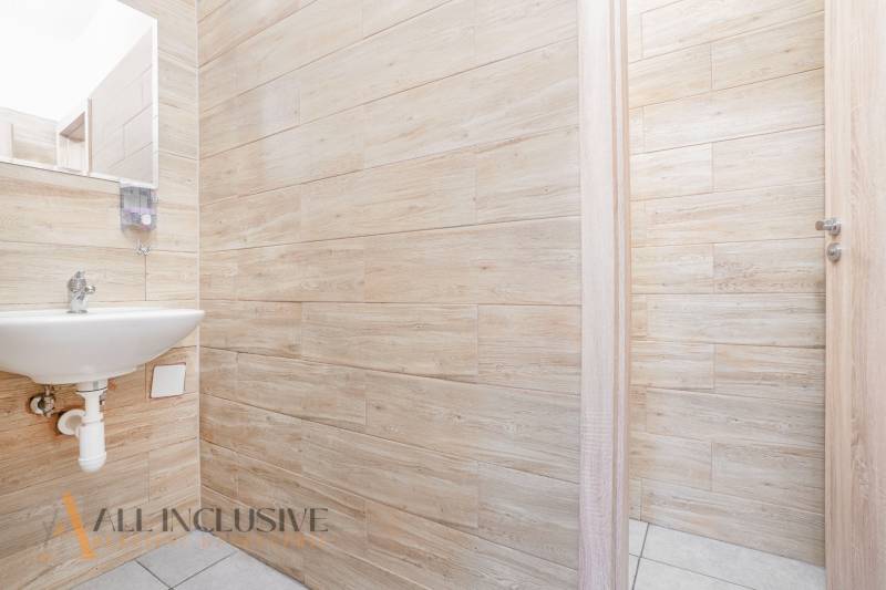 Büroinnenraum mit Waschbecken, Holzwänden und offener Tür.