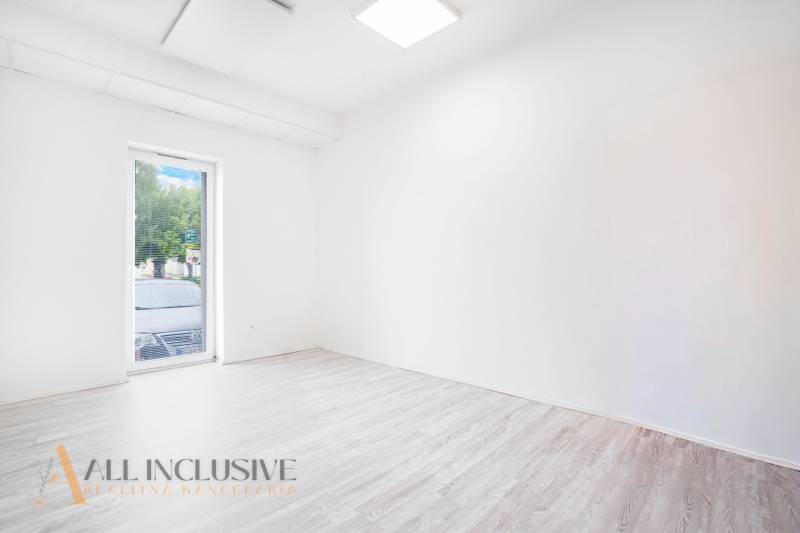 Ein leeres Büro mit einem Boden in Holzoptik und einem großen Fenster.