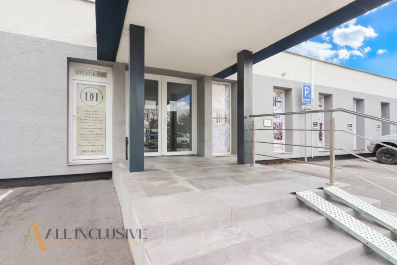 Eingang zu den Geschäftsräumen in der Vajanského-Straße, mit barrierefreiem Zugang und einem Parkplatz.