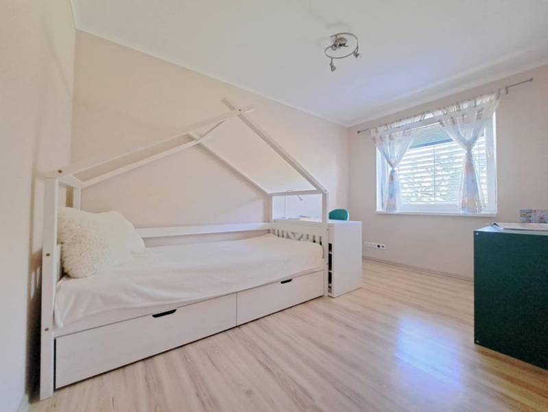 Kinderzimmer in einem Einfamilienhaus mit einem Bett in Form eines Häuschens und einem Boden mit Holzdekor.