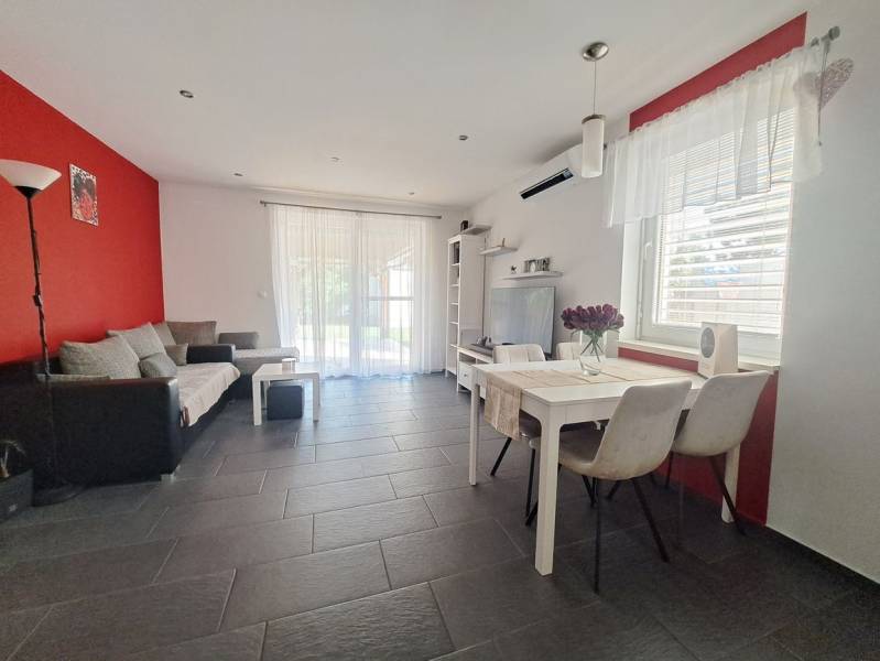 Wohnzimmer in einem Einfamilienhaus mit roter Wand, grauen Fliesen und weißen Möbeln.