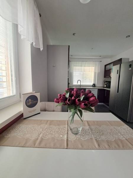 Eine Küche in einem Einfamilienhaus mit einer Vase voller Tulpen auf dem Tisch und weißen Vorhängen.