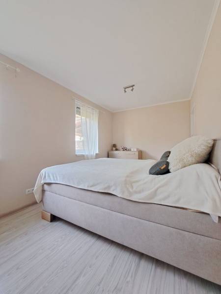 Helles Schlafzimmer in einem Einfamilienhaus mit bequemem Bett und Boden in Holzoptik.