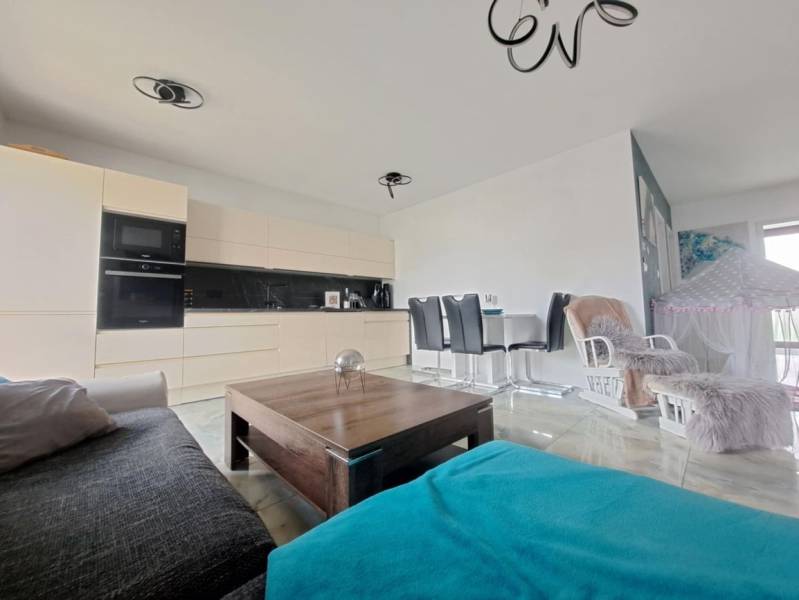 Wohnzimmer in einem Einfamilienhaus mit offener Küche und Esstisch. Boden mit Holzdekor.