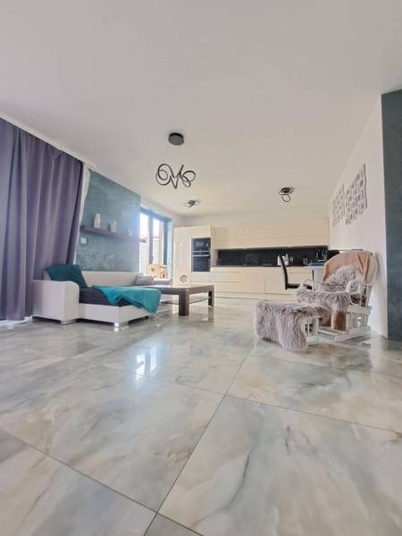 Wohnzimmer mit großen Fenstern und hellen Fliesen in einem Einfamilienhaus.