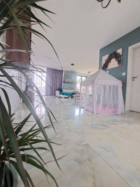 Innenraum eines Einfamilienhauses mit einem Zelt für Kinder auf einem glänzenden Boden und Pflanzen.