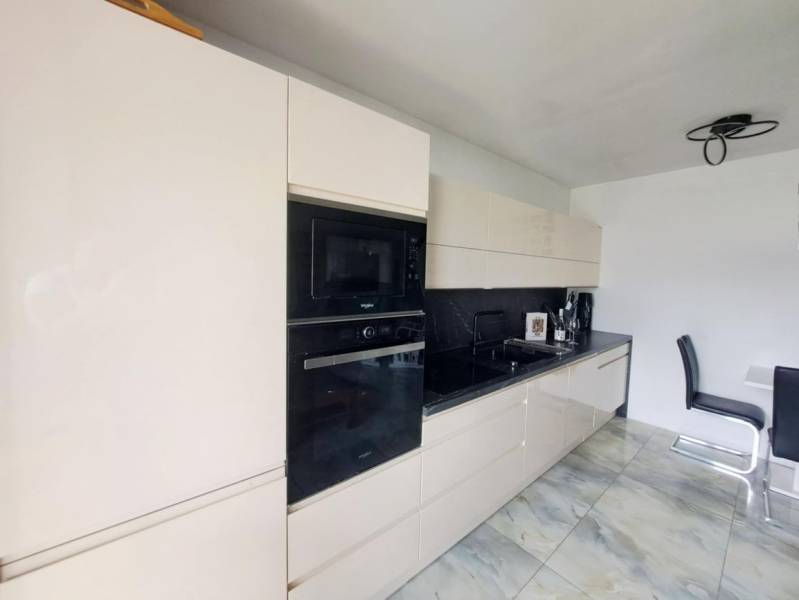 Küche in einem Einfamilienhaus mit glänzender Küchenzeile und eingebauten Geräten, Boden mit Marmormuster.