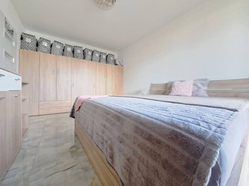 Schlafzimmer in einem Einfamilienhaus mit Doppelbett, Schrank und Boden mit Holzdekor.