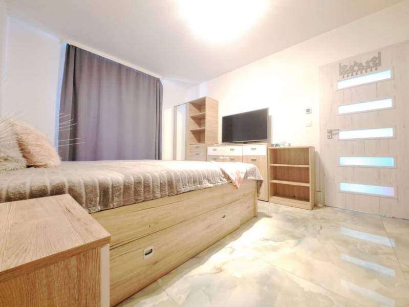 Schlafzimmer im Einfamilienhaus mit Bett, Kleiderschrank, Fernseher und Boden mit Holzdekor.