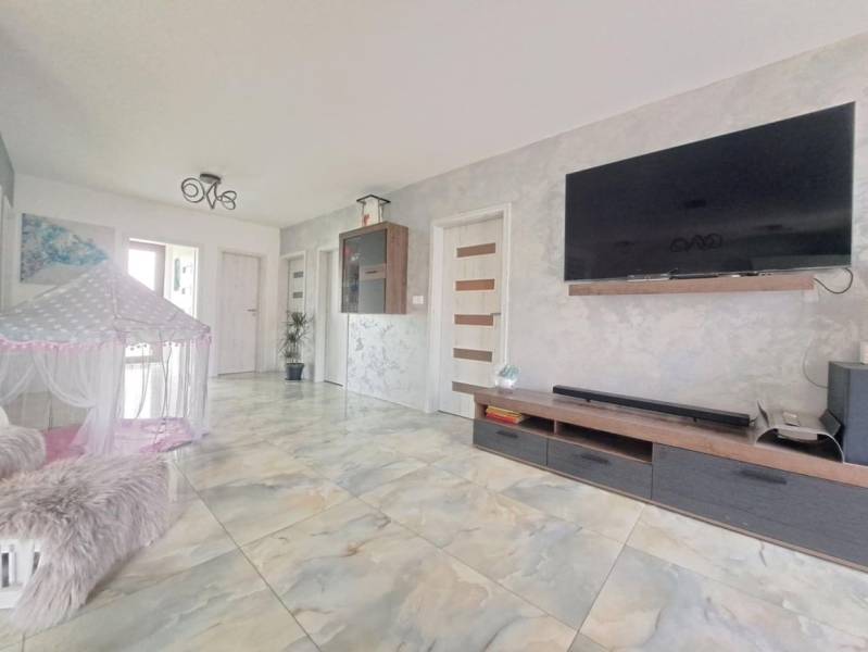 Wohnzimmer in einem Einfamilienhaus mit einem Fernseher an der Wand, einem Zelt und einem Keramikboden.