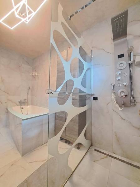 Badezimmer mit moderner Dusche, Badewanne und Designerbeleuchtung in einem Einfamilienhaus.