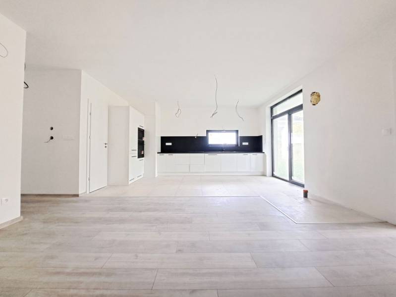 Geräumige Küche mit schwarzen Fliesen und Boden in Holzoptik in einem Einfamilienhaus.