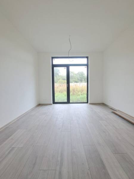 Innenraum eines Einfamilienhauses mit Holzboden und großem Fenster.