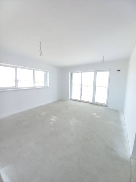 Ein geräumiges Zimmer in einer 2-Zimmer-Wohnung mit hellen Wänden und großen Fenstern.