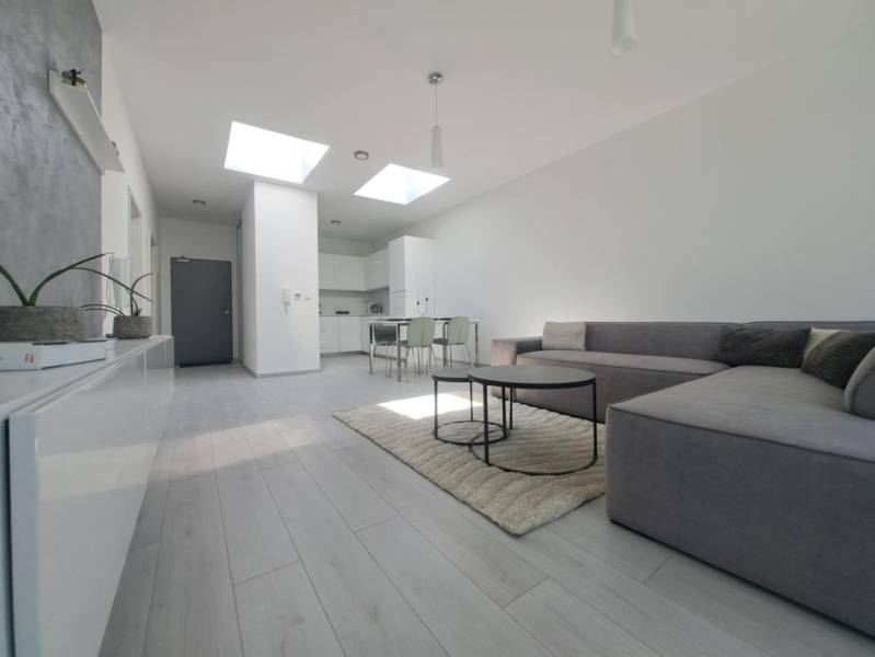 Wohnzimmer mit Sofa, Holzboden und Esstisch in einer Zweizimmerwohnung.