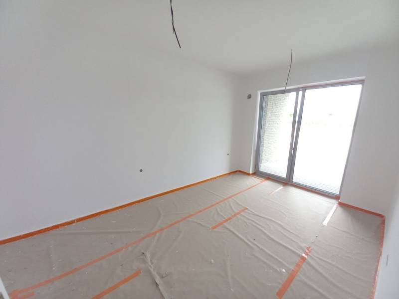 Gewerbefläche mit großem Fenster, weiße Malerei, Boden mit Holzdekor mit Folie abgedeckt.