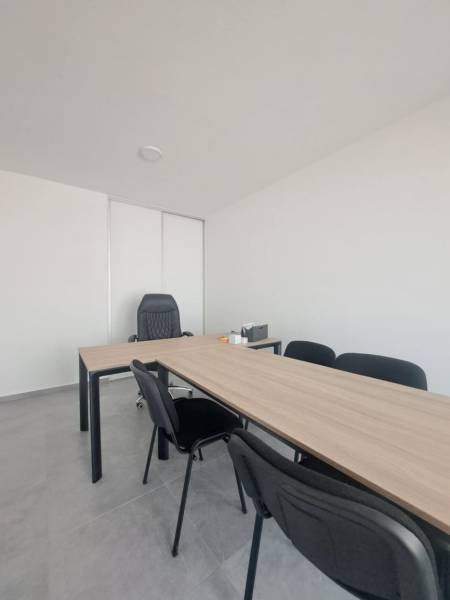 Bürotische und schwarze Stühle in Geschäftsräumen mit minimalistischem Interieur.