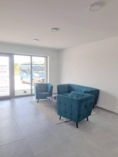 Gewerbeflächen mit türkisfarbenen Sitzgelegenheiten, grauem Boden und großem Fenster.