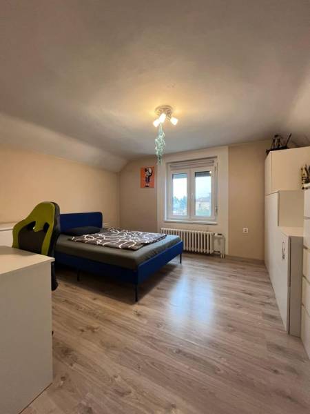 Schlafzimmer in einem Einfamilienhaus mit Holzdekorboden, Bett und Schreibtisch.