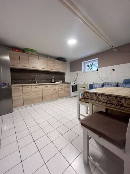 Eine Küche in einem Einfamilienhaus mit Fliesen, Holzschränken, einem Kühlschrank und einem Esstisch.