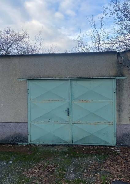 Garagentor mit hellblauen Türen und abgefallenen Blättern in Selice.