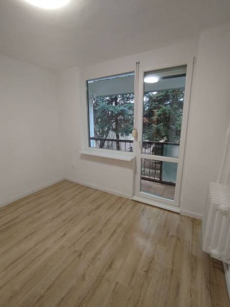 Ein Zimmer mit hellen Wänden, einem Boden in Holzoptik und Blick ins Grüne.