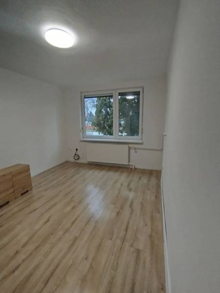 Helles Zimmer mit Holzboden und Fenster in einer 3-Zimmer-Wohnung.