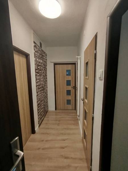 Ein Flur mit hellem Boden und Holztüren in einer 3-Zimmer-Wohnung.