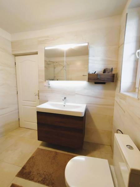 Ein Badezimmer in einem Einfamilienhaus mit weißen Wänden und einem Waschbecken mit Spiegel.