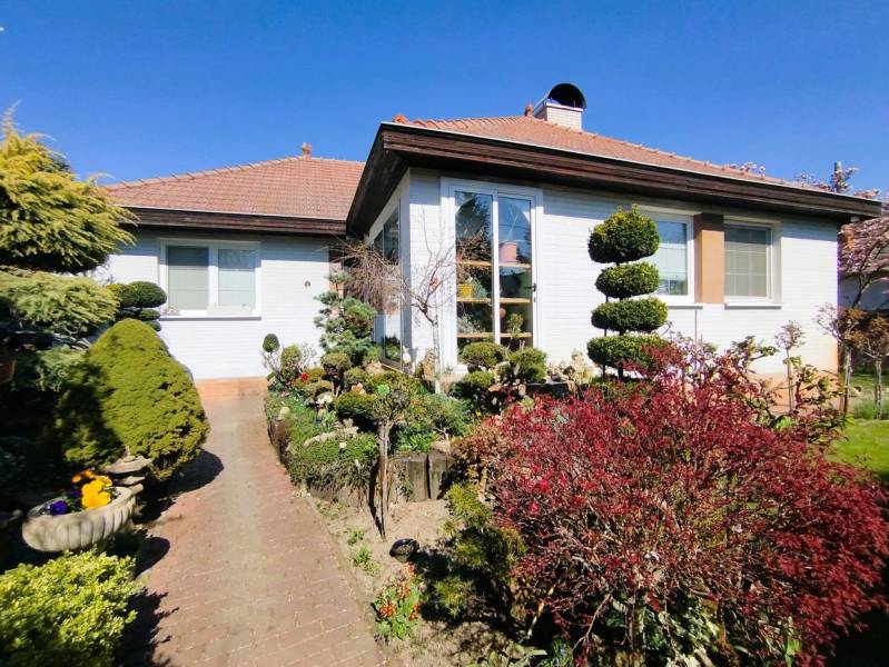 Ein Einfamilienhaus in Šaľa mit gepflegtem Garten, Gehweg und Grünflächen unter blauem Himmel.