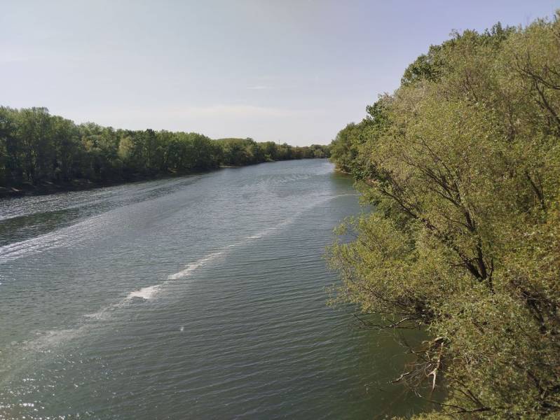 Ein von Grün umgebener Fluss in den Gärten von Šaľa bei ruhigem, sonnigem Wetter.