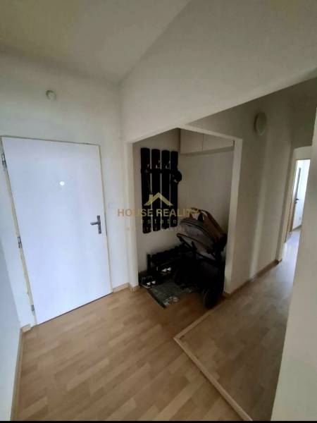 Flur in einer 4-Zimmer-Wohnung mit Garderobe, Kinderwagen und Boden in Holzoptik.
