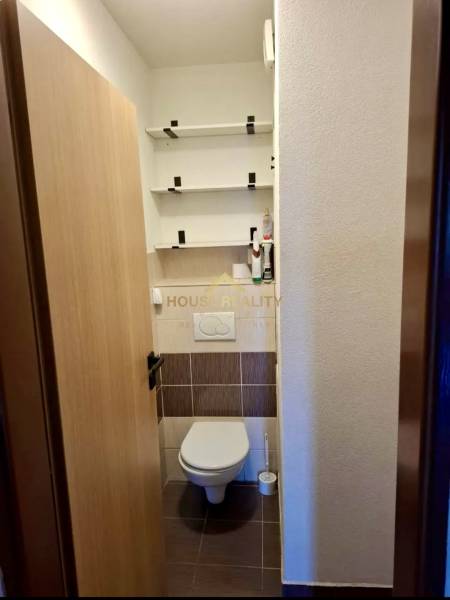 Toilette mit Wandregalen in einer 4-Zimmer-Wohnung, Boden mit Holzdekor.